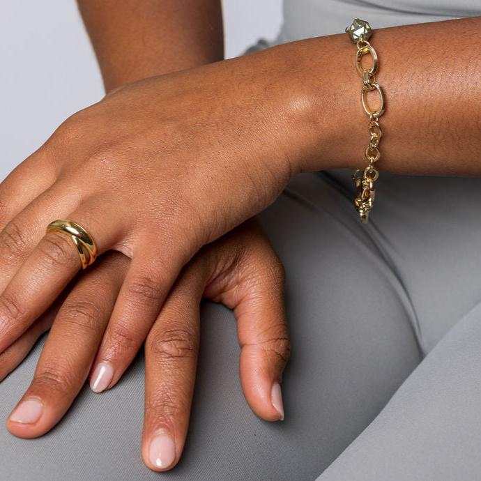 Gold-toned double band minimalist ring on a person's hand showcasing intertwined design and sleek elegance.