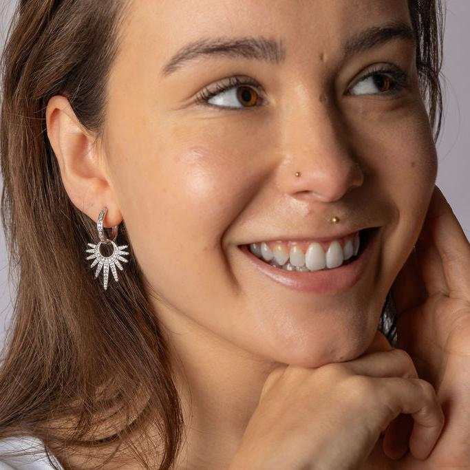 Woman wearing Shimmering Crescent Hoops with starburst design and sparkling cubic zirconia.